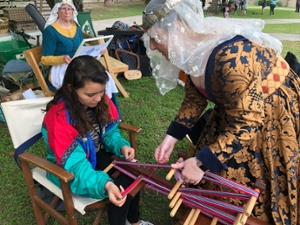 A student learning a medieval weaving technique.