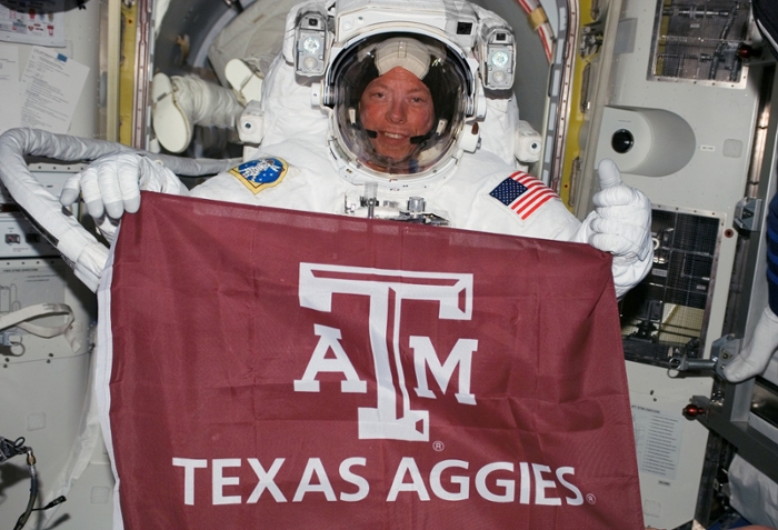 Col. Michael E. Fossum '80 poses with a Texas A&M flag while aboard the International Space Station