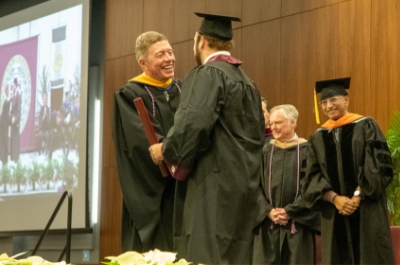 A graduate shakes the hand of Colonel Michael E. Fossum at December Commencement at Texas A&M University at Galveston.