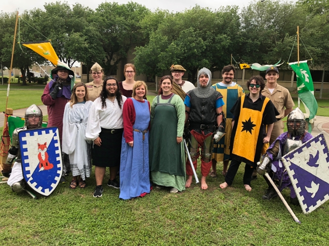 Dr. Katherine Echol's Arthurian Lit class poses with two armor-clad Society for Creative Anachronisms (SCA) members.