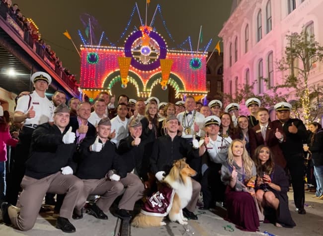 Students and leaders of the Texas A&M University at Galveston, alongside members of the Texas A&M Corps of Cadets and Aggie mascot Reveille X, pose for a photo in the middle of the Knights of Momus Grand Night Parade during 2022's 7th Annual Mardi Gras Parade & Viewing Party at the Tremont House in Galveston.  